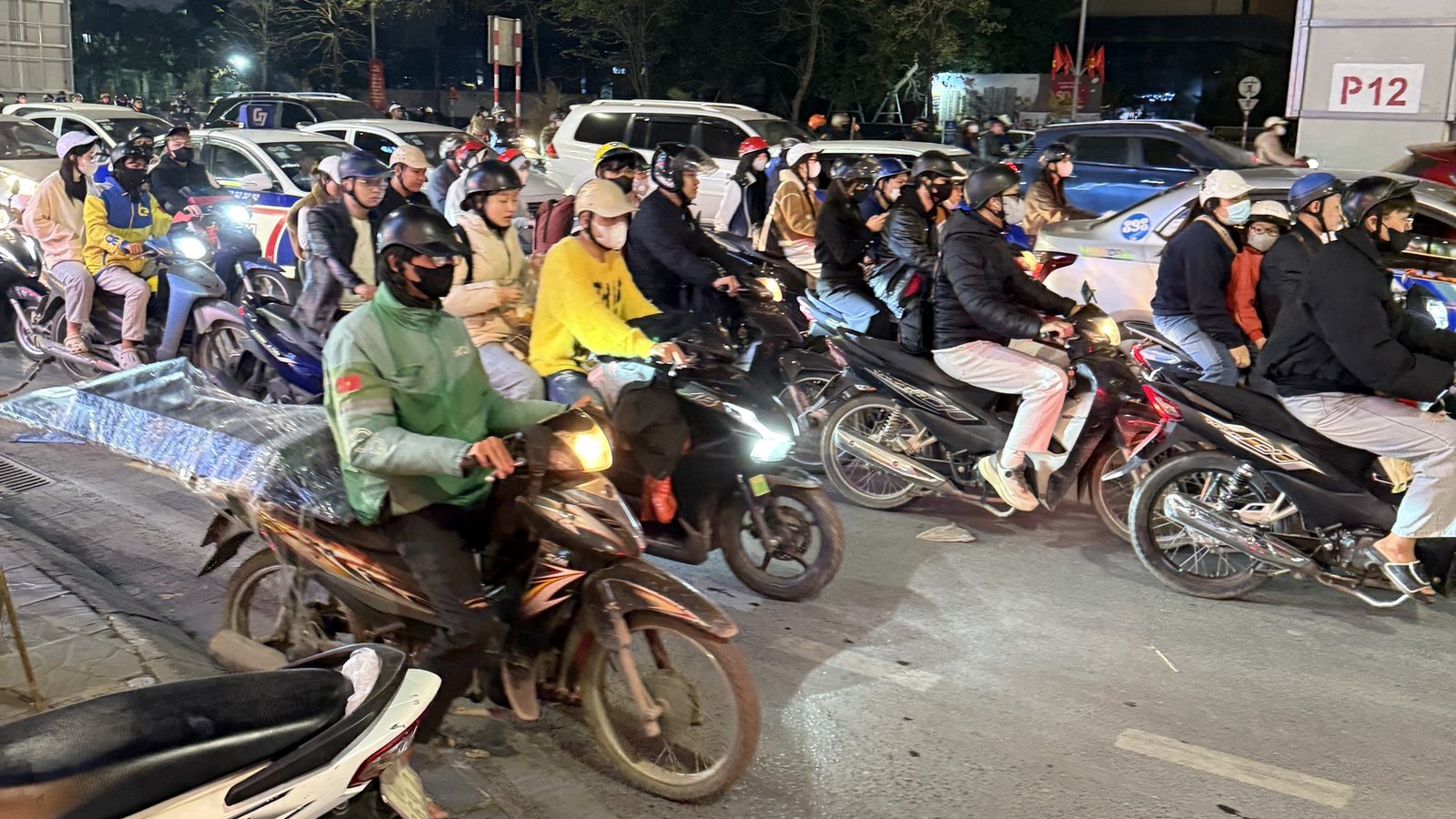 Editorial image of dense Hanoi night traffic under an overpass, used as the hero for a ChaosCB ranking of Hanoi districts by expat quality of life